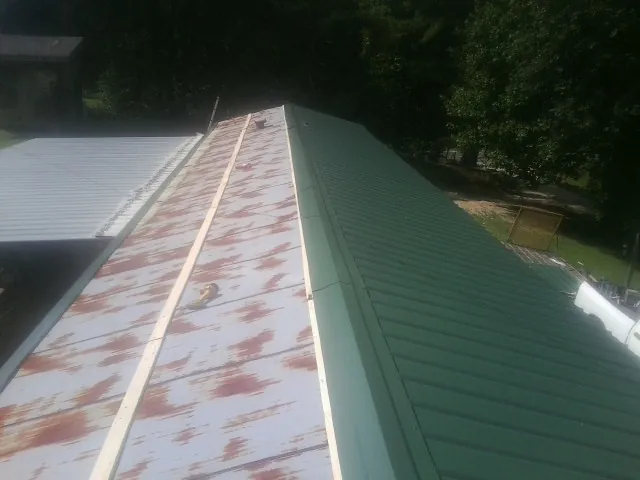Old rusted panels beside newly installed green metal roofing — Wind Damage Roof Repair by Roofing Brothers in Moulton