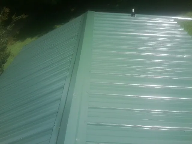 New green metal panels meeting at the ridge of a roof — Flat Roof Repair work by our crew in Moulton