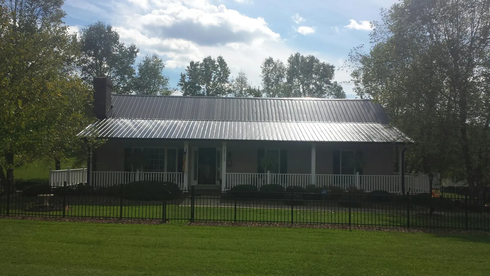 Gray metal roof on a brick ranch with a full width front porch — Gutter Guard Installation work by our crew in Moulton
